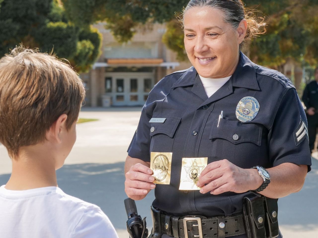 The Art of Drawing Readers In: Your attractive post title goes here A friendly police officer shows a badge to a young boy in a community setting.